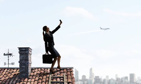 Businesswoman catching moment on her mobile . Mixed mediaの写真素材