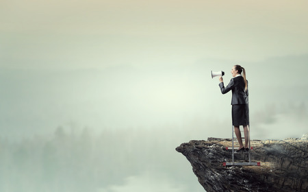 Woman standing on ladder and making announcement in megaphone . Mixed mediaの写真素材