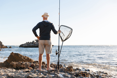 Senior man fishing at sea sideの写真素材