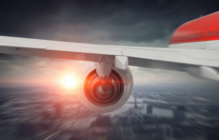 Wing of airplane taking off above modern cityscape . Mixed media