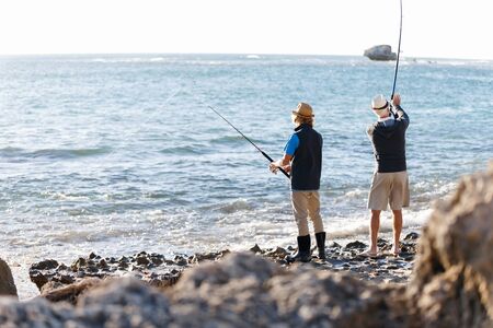 Senior man fishing with his grandsonの写真素材