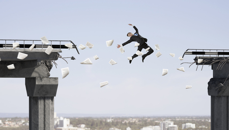Businessman jumping over a gap in the bridge as a symbol of courage. Mixed mediaの写真素材