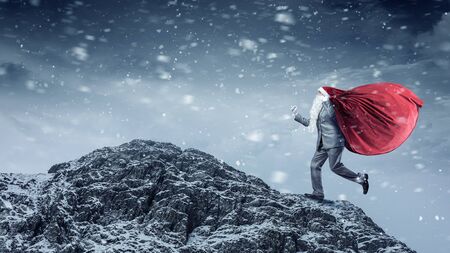 Businessman in Santa hat running with bag on back. Mixed mediaの写真素材