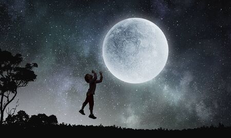 Silhouette of happy boy jumping to touch full moon. Mixed media
