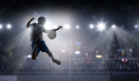 Silhouette of soccer player jumping and kicking ball at stadium . Mixed mediaの写真素材