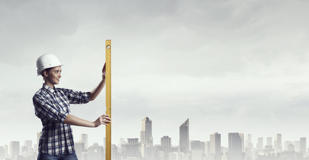 Builder woman taking measures . Mixed mediaの写真素材