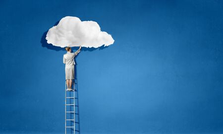 Businesswoman standing on ladder that lead to skyの写真素材