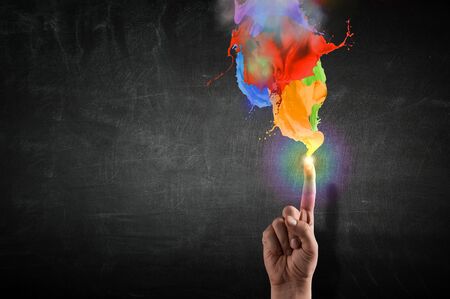 Close up of hand pointing with finger at splashes of colorful paint