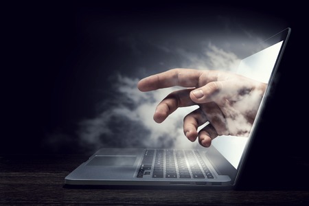 Hand which seems to come out of laptop screen. Mixed mediaの写真素材