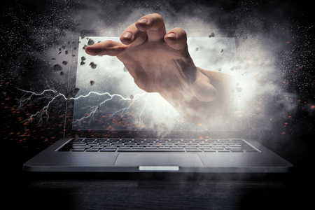 Hand coming from notebook screen. Mixed mediaの写真素材