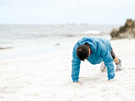 Young man doing exercise at the beachの写真素材