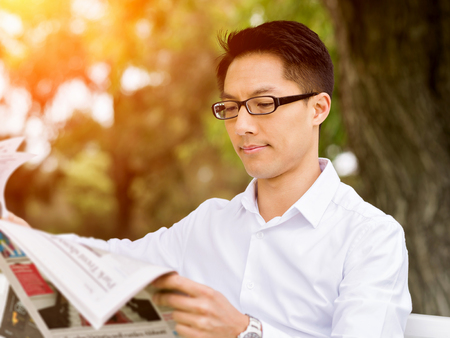 Business man reading a newspaper in parkの写真素材