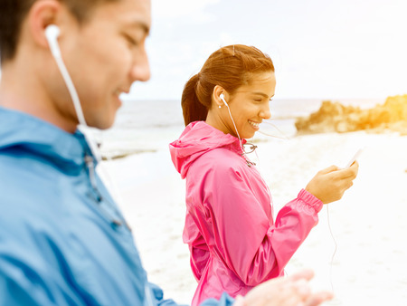 Sporty young couple with earphones on the sea coastの写真素材