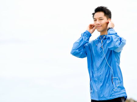 Sporty man with earphones on the sea coastの写真素材