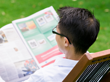 Business man reading a newspaper in parkの写真素材