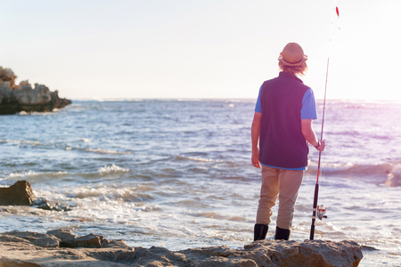 Teenage boy fishing at seaの写真素材
