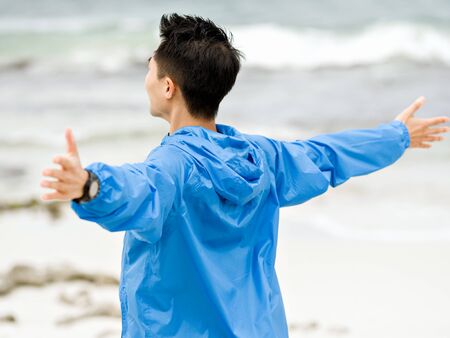 Young man with outstretched arms at the beach