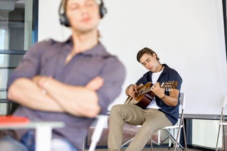 Young man playing the guitar in officeの写真素材