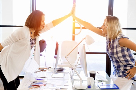 Two young women in office celebrating successの写真素材