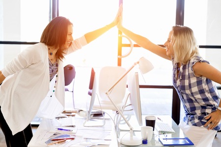 Two young women in office celebrating success