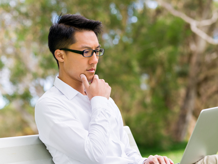 Young businessman using laptop while sitting outdoorsの写真素材
