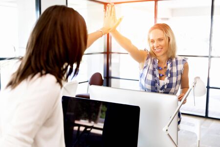 Two young women in office celebrating success