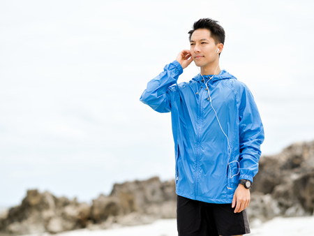 Sporty man with earphones on the sea coast