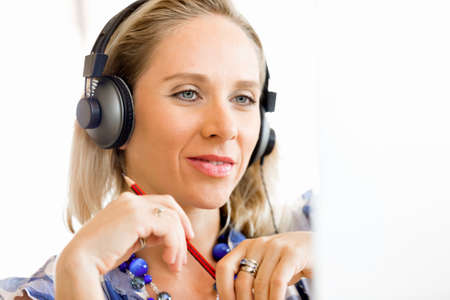 Young woman in the office with headphonesの写真素材