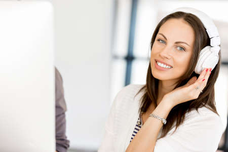 Young woman in the office with headphones