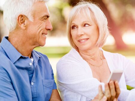 Happy senior couple looking at smartphone