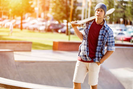 Teenage boy with skateboard standing outdoorsの写真素材