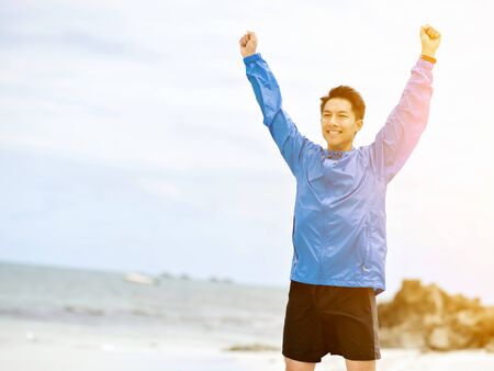 Young man with outstretched arms at the beachの写真素材