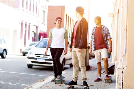 Teenage friends walking at the street with skateboardsの写真素材
