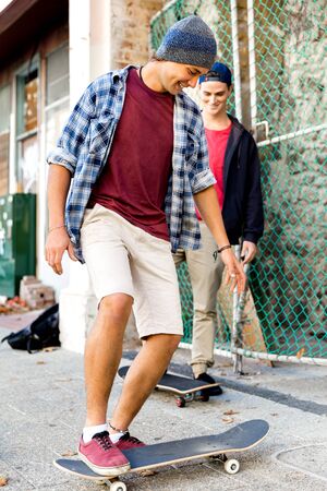 Teenage friends walking at the street with skateboards