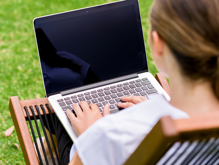 Young business woman sitting in park and working with laptopの写真素材