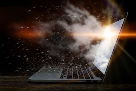 Opened laptop with light coming from screen on dark background. Mixed mediaの写真素材