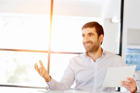 Handsome young man holding paper in officeの写真素材
