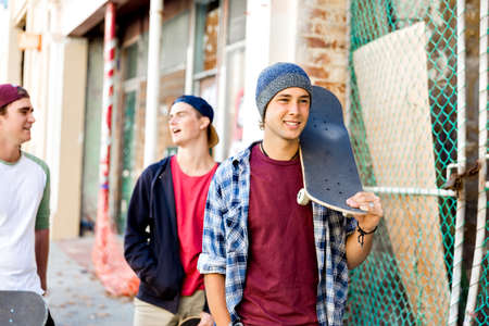 Teenage friends walking at the street with skateboardsの写真素材