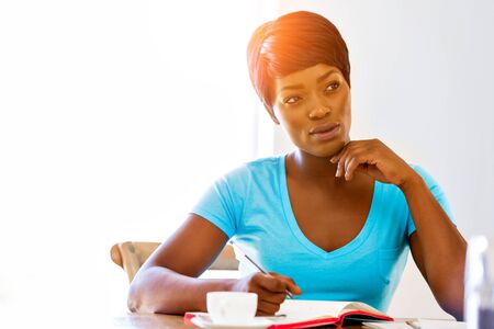 Young woman writing in an agenda at home or officeの写真素材