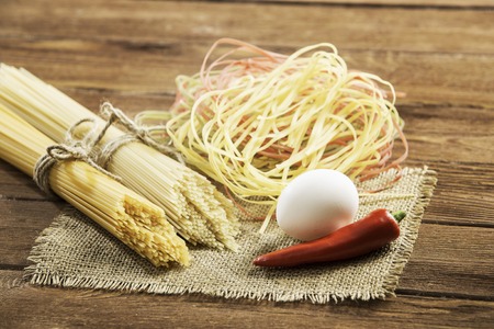 Dry spaghetti pasta and eggs on table ready for cookingの写真素材