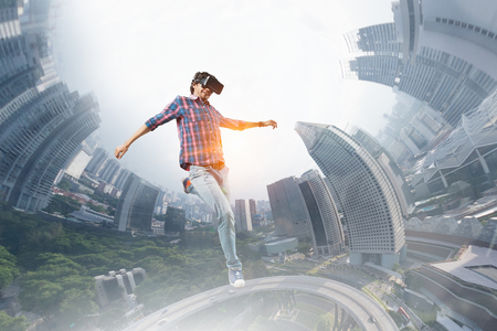 Young man in checked shirt and headset experiencing virtual reality. Mixed mediaの写真素材
