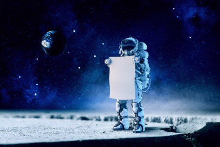 Astronaut in space holding white blank board. Mixed mediaの写真素材