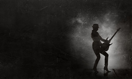 Silhouette of woman play guitar on concrete backgroundの写真素材