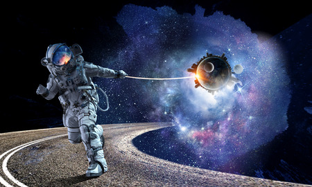 Astronaut in outer space pulling planet on rope. Elements of this image are furnished by NASAの写真素材