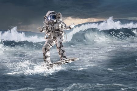 Spaceman on flying board surfing the sea. Mixed mediaの写真素材