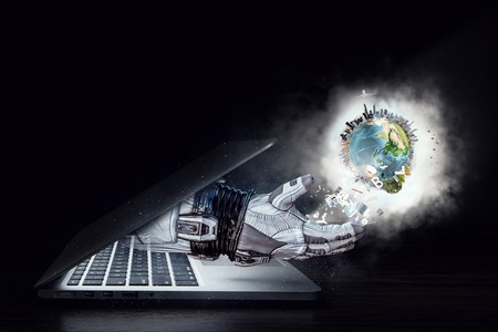 Hand of astronaut coming out of laptop screen.の写真素材