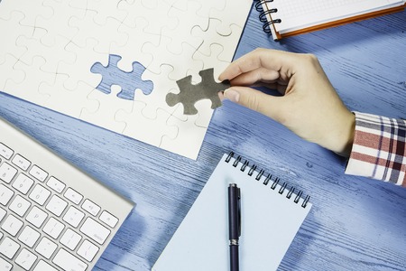Hand of woman completing puzzle with missing piece