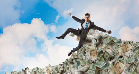 Rich businessman in pile of money banknotesの写真素材