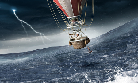 Color aerostat flying above stormy sea waves and businessman looking in spyglassの写真素材