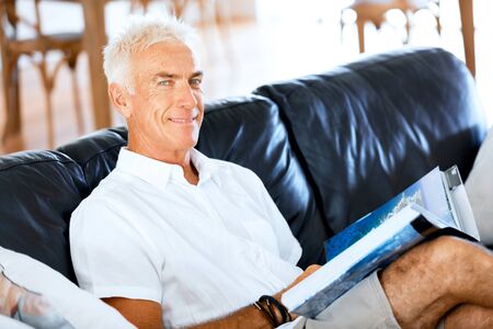 Handsome sennior man reading a book relaxing on a sofa
